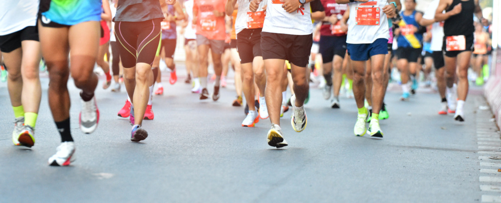 Multiple people running a marathon in early morning on pavement.