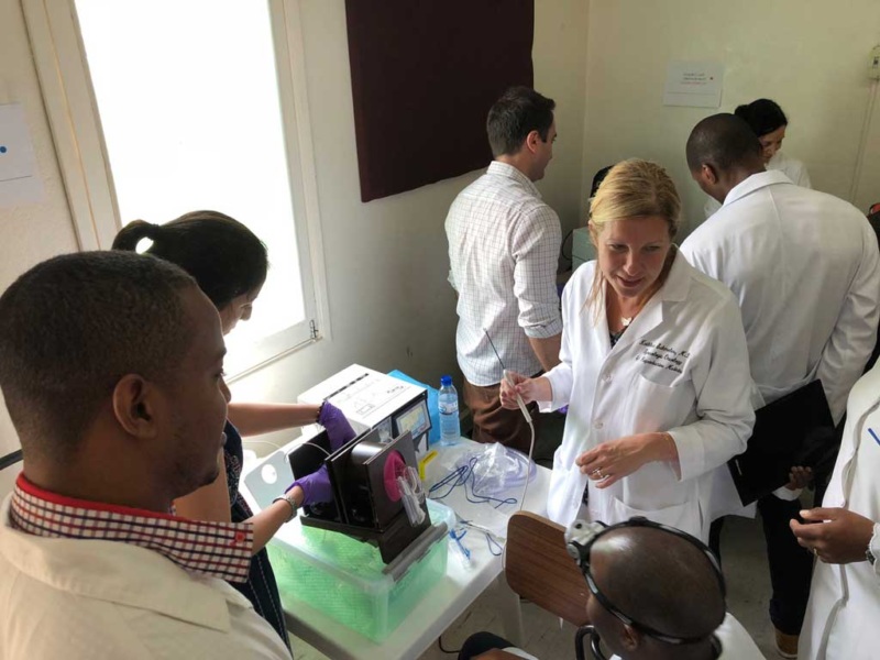 Dr. Kathleen Schmeler holding a medical instrument and surrounded by a group of local nurses and doctors in Mozambique, Brazil