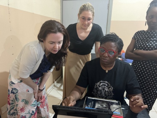 Women huddled around a computer screen. One is sitting and three others stand behind her.